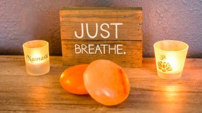 Relaxing massage candels. Hot stones for massage and a sign that says, Just Breathe.